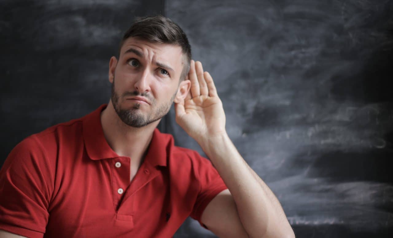 man putting hand up to ear