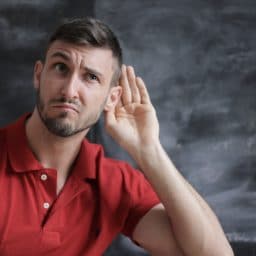 man putting hand up to ear